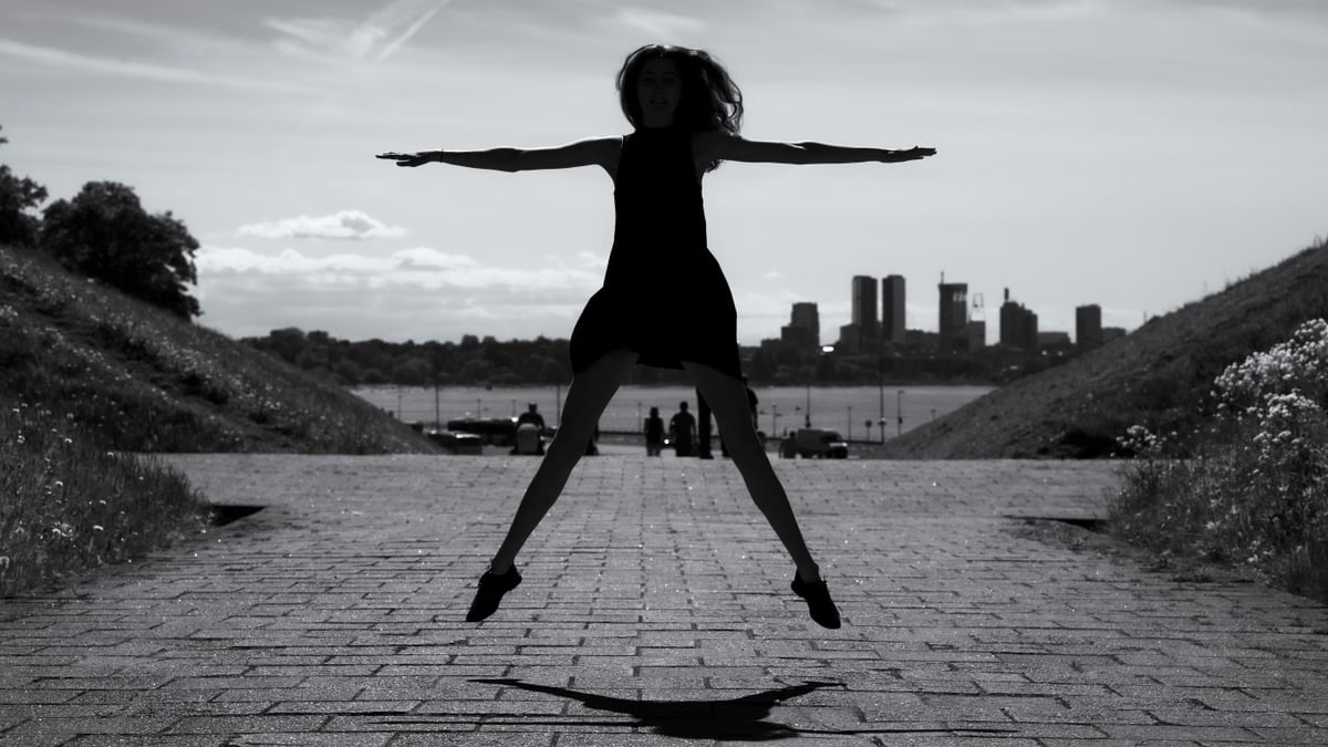 A dynamic black and white silhouette of a woman jumping with arms outstretched in Tallinn, Estonia.